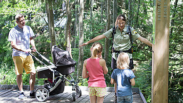 Vater gemeinsam mit seinen drei Kindern und einer Wanderführerin auf einer Kinderwanderung im Schwarzwald.