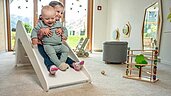 Baby rutscht mit großer Schwester auf der Babyrutsche im Happy-Club im Familienhotel Almfamilyhotel Scherer in Tirol.
