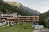 Außenansicht des Familienhotel Bella Vista in Südtirol mit Neubau, großer Wiese, Poolbereich und Bergkulisse.