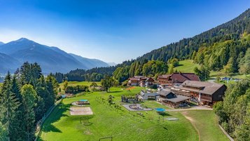 Großzügige Außenanlage des Familienhotels Ramsi in Kärnten mit Spielplatz, Sportbereich und Panoramablick auf die Berge