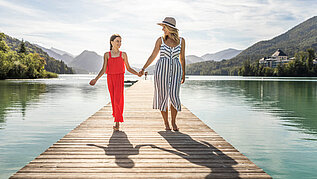 Salzburger Land Ausflugstipps: Mutter und Tochter stehen Hände haltend auf dem Steg vom Hofer Badesee.