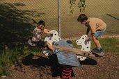 Zwei Kungs sitzen auf einer Wippe auf dem Spielplatz des Familienhotels Engel Gourmet & Spa in Südtirol