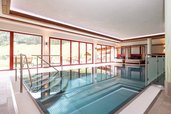 Moderner Indoor-Pool mit großen Panoramafenstern und Relaxliegen im Familienhotel Oberkarteis.
