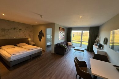 Heller Elternschlafbereich mit Doppelbett, Sitzecke und Blick ins Grüne im Familienhotel Gut Landegge