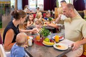 Im Familienurlaub wird eine umfangreiche Verpflegung angeboten. Eine Familie sitzt gemeinsam im Familienhotel Rhön Feeling im Restaurant beim Essen.