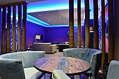 Stylische Lounge mit blauer Beleuchtung im Familienhotel Sonnenhügel, ausgestattet mit modernen Sitzgelegenheiten, Bambussäulen und zeitgenössischer Kunst.