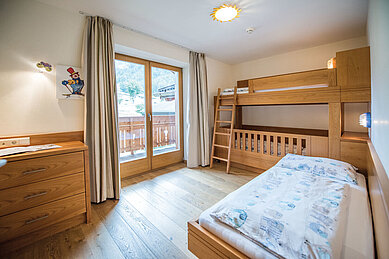 Kinderzimmer in der Familiensuite des Familienhotels Huber in Südtirol mit Stockbett und Einzelbett.