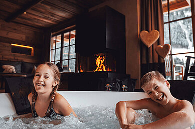 Kinder sitzen im privaten Chalet-Whirlpool im Familienurlaub im Mons Silva Private Luxury Chalet.