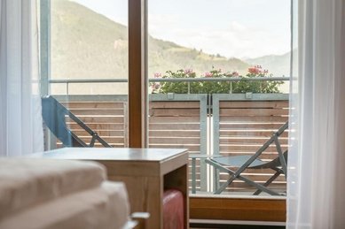 Balkon mit Sitzgelegenheit und Blick in die Natur im Familienhotel Amiamo im Salzburger Land.