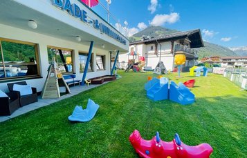 Große Spielwiese mit Kletterstein, Tracktoren und Fußballtor im Wellness- & Familienhotel Egger in Saalbach Hinterglemm.