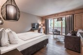 Modern eingerichtetes Familienzimmer im Familienhotel Engel Gourmet und Spa mit Doppelbett, Sitzecke und Balkon.