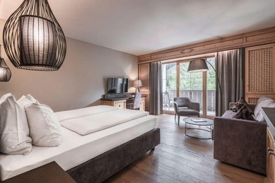 Modern eingerichtetes Familienzimmer im Familienhotel Engel Gourmet und Spa mit Doppelbett, Sitzecke und Balkon.