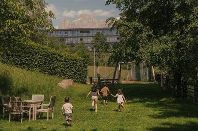 Kinder rennen lachend über den Garten des Familienhotels Engel Gourmet & Spa in Südtirol