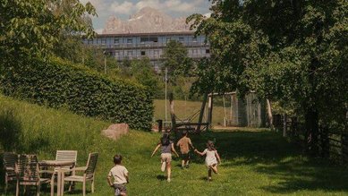 Kinder rennen lachend über den Garten des Familienhotels Engel Gourmet & Spa in Südtirol