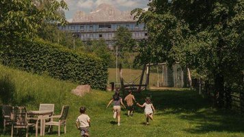 Kinder rennen lachend über den Garten des Familienhotels Engel Gourmet & Spa in Südtirol