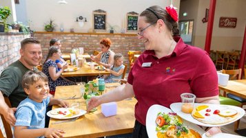 Familie wird im Restaurant des Familienhotels Family Club Harz von einer freundlichen Bedienung bedient.