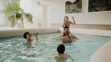Eine Familie badet im Hallenbad des Hotel Sonngastein im Salzburger Land mit hellem Poolbereich und großen Fenstern.