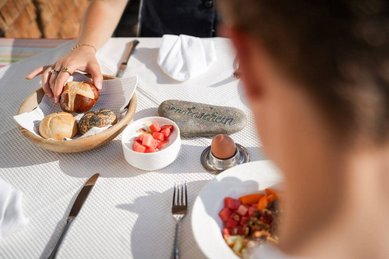 Frühstückstisch mit Brotkorb, Obstschale und Ei im Familienhotel Sonne Bezau.