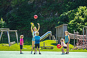 Kinder spielen mit dem Ball auf dem Fußballplatz im Familienhotel Sonne Bezau Vorarlberg.