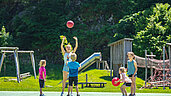 Kinder spielen mit dem Ball auf dem Fußballplatz im Familienhotel Sonne Bezau Vorarlberg.