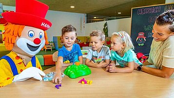 Das Maskottchen Happy spielt mit den Kindern im Spielzimmer vom Alphotel Tyrol Wellness & Family Resort in Südtirol.