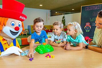 Das Maskottchen Happy spielt mit den Kindern im Spielzimmer vom Alphotel Tyrol Wellness & Family Resort in Südtirol.