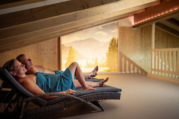 Eltern entspannen im Ruheraum mit Bergblick des Familienhotels Krone im Allgäu.