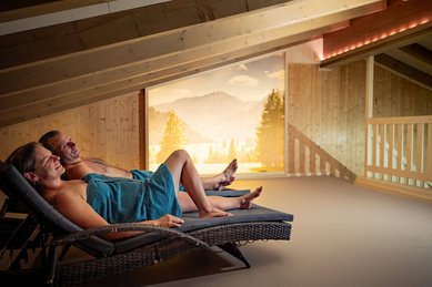 Eltern entspannen im Ruheraum mit Bergblick des Familienhotels Krone im Allgäu.