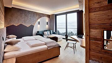 Gemütlich eingerichtetes Elternschlafzimmer "Glückspilz" mit großer Fensterfront im Familienhotel Allgäuer Berghof in den Allgäuer Alpen.