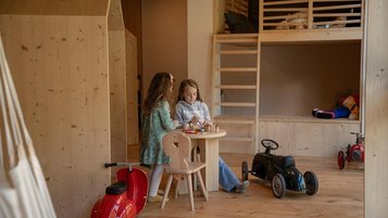 Kinder spielen im Spielbereich der Kinderbetreuung im Hotel Bella Vista in Südtirol.