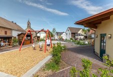 Spielplatz im Familienhotel Ottonenhof im Sauerland mit Schaukel und Blick auf den Innenhof.