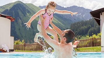 Papa und Tochter planschen im Pool vom Familienhotel Kaiserhof Tiroler Zugspitzarena.