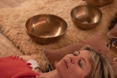 Eine Frau liegt entspannt bei einer Wellnessbehandlung mit Klangschalen im Hotel Bella Vista in Südtirol.