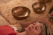 Eine Frau liegt entspannt bei einer Wellnessbehandlung mit Klangschalen im Hotel Bella Vista in Südtirol.