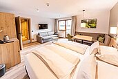Genütlicher Schlafraum mit einem Doppelbett und einer Wohnecke das viel Tageslicht hat im Familienhotel Das Bayrischzell in Oberbayern.