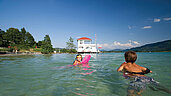Zwei Kinder planschen fröhlich im klaren See in Kärnten.
