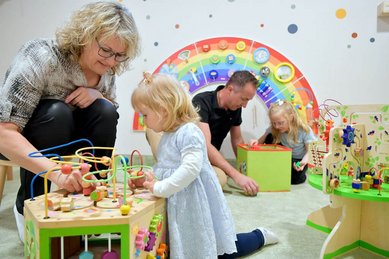 Eltern und Kinder spielen gemeinsam im liebevoll gestalteten Indoor-Spielraum für Kleinkinder im Familienhotel Rhön Feeling.