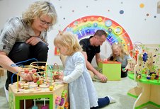 Eltern und Kinder spielen gemeinsam im liebevoll gestalteten Indoor-Spielraum für Kleinkinder im Familienhotel Rhön Feeling.