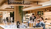 Familie wählt am Frühstücksbuffet des Zauchenseehofs aus verschiedenen Cerealien und Zutaten aus und genießt die moderne, helle Buffetstation.