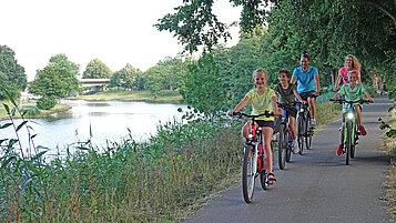 Eine Familie radelt auf einem Weg den Dortmund-Ems-Kanal entlang.