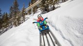 Mutter und Kind rodeln voller Freude die Rodelstrecke hinunter im Familienurlaub im Familienhotel Galtenberg Family & Wellness Resort in Tirol.