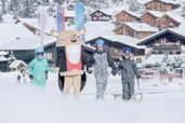 Kinder im Winter mit einem Maskottchen vor dem Familienhotel Gorfion in Liechtenstein.