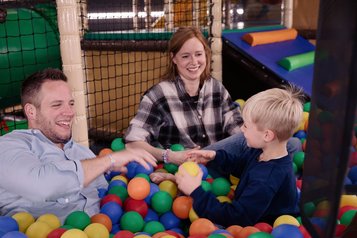 Vater und Mutter spielen mit ihrem Sohn im Bällebad im Familienhotel Seeklause.