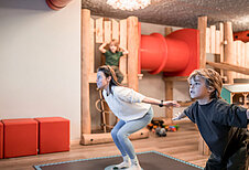 Mutter spielt mit ihren beiden Kindern auf dem Indoor-Spielplatz des Familienhotels Alpenhof Dolomit Family