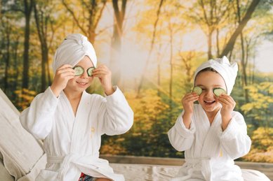 Kinder mit Bademänteln und Gurkenscheiben bei der Wellnesszeit im Familienhotel Das Bayrischzell