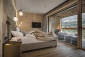 Gemütliches Schlafzimmer im Familienhotel Mia Alpina in Tirol mit großem Bett, Terrasse und Blick auf die Berge.