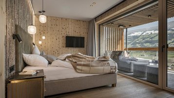 Gemütliches Schlafzimmer im Familienhotel Mia Alpina in Tirol mit großem Bett, Terrasse und Blick auf die Berge.