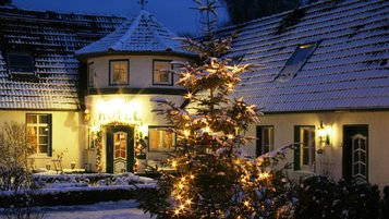 Der Eingangsbereich von Borchards Rookhus ist weihnachtlich geschmückt, ein leuchtender Weihnachtsbaum steht im verschneiten Innenhof des Familienhotels.