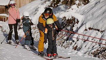 Eine Familie fährt mit dem Ski-Lift die Kinderhang hoch.