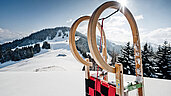 Ein großer Holzschlitten steht im Schnee.